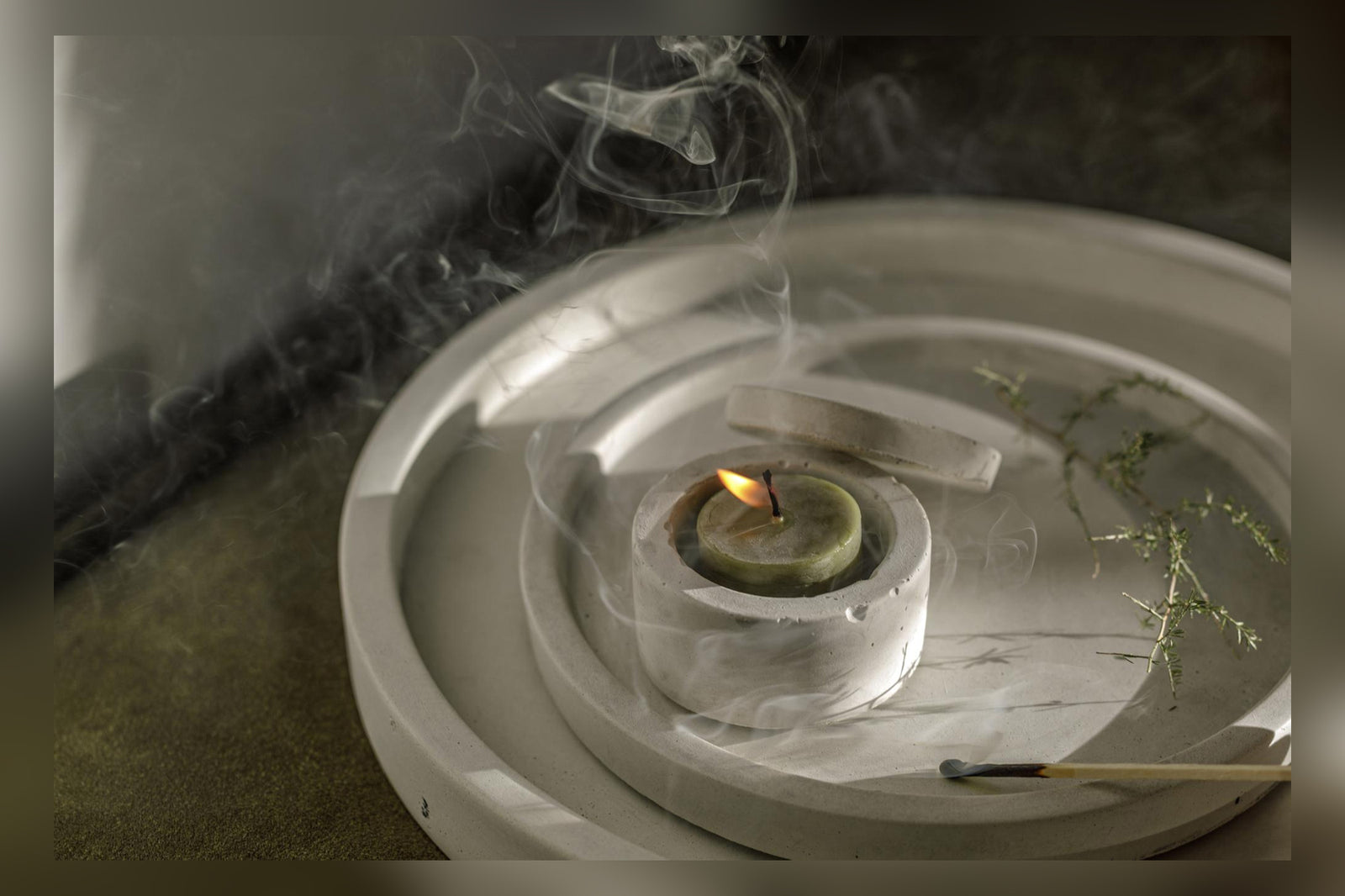 Lit candle on a plate with delicate smoke wisps rising gracefully.