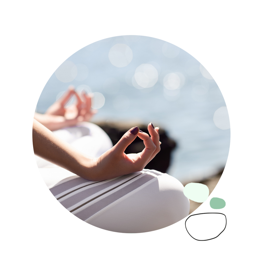 Person meditating by the sea, close-up on hands in a mudra pose.