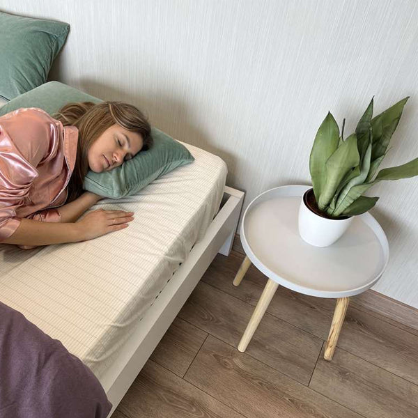A woman peacefully sleeping on a mattress in a cozy bedroom, surrounded by soft bedding and warm lighting.