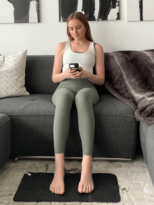 A woman seated on a couch, engaged with her phone, exuding a relaxed and focused demeanor.